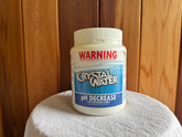 A plastic container labeled 'Crystal Water pH Decrease' intended for use in swimming pools and spa pools. Sulis hot tube cleaner